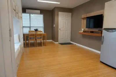 an empty living room with a table and a refrigerator at ALTEAN Apartments - Isabela Room in Manila