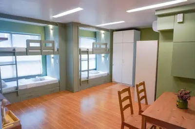 a room with two bunk beds and a table and chairs at ALTEAN Apartments - Lourdes Room in Manila