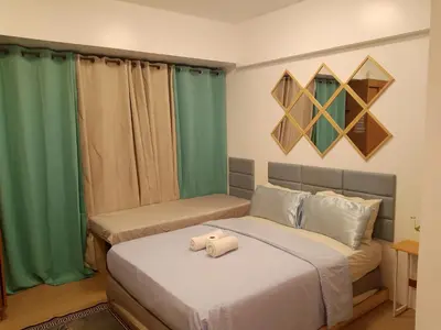 two beds in a room with green curtains at Avah de lara condotel NAIA T3 in Manila