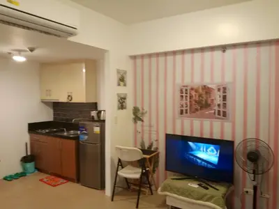 a living room with a tv and a kitchen at Avah de lara condotel NAIA T3 in Manila