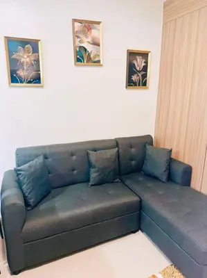 a couch in a living room with pictures on the wall at Shabby Chic & Contemporary Condo in Manila