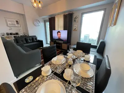 a living room with a dining table and a television at 8 Adriatico - 1 Bedroom with 1 Parking Space near SLMEC, PGH and US Embassy in Manila