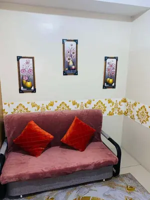 a red couch in a room with three mirrors at Triple 3D Shell Residences in Manila