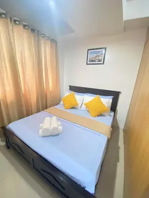 a bedroom with a bed with yellow and white pillows at YUYANS Staycation Shell Residences in Manila