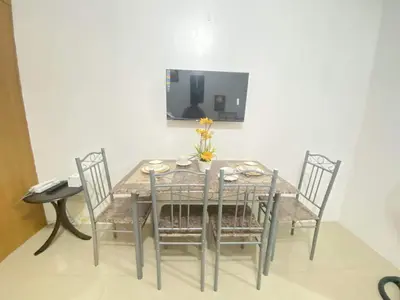 a dining room table with four chairs and a television at YUYANS Staycation Shell Residences in Manila