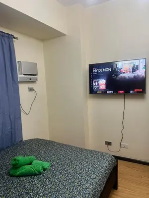a bedroom with a bed with a tv on the wall at Sundawn RadianceManilaBay in Manila