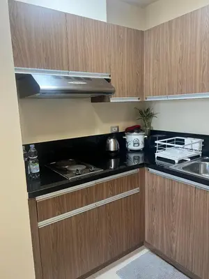 a kitchen with wooden cabinets and a stove top oven at Sundawn RadianceManilaBay in Manila