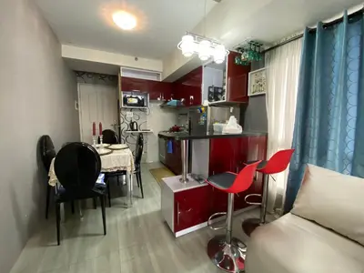 a living room with red cabinets and a table and chairs at Avida Tower San Lorenzo in Manila
