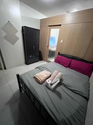 a bedroom with a bed with two towels on it at JAL's Cozy Haven in Manila