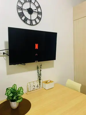 a tv on a wall above a table with a clock at SMDC Light Residences Condominium in Manila