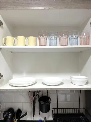 a shelf with glasses and plates and utensils at Cozy Two Bedroom Family Suites at Coast Residences near PICC, WTC & MOA in Manila