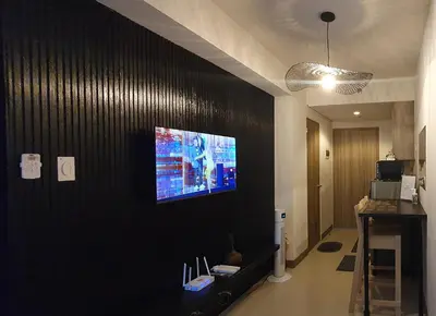 a living room with a tv on a black wall at C Place - Capsule B - Upper in Manila