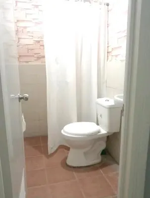 a bathroom with a toilet and a white shower curtain at Elegant 2BR Condo unit with free WiFi in Anabu Primero