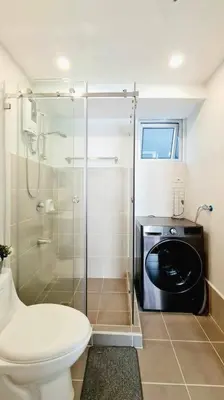 a bathroom with a toilet and a glass shower at California Themed Condo in BGC in Manila