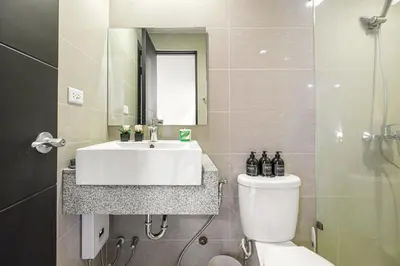 a bathroom with a sink and a toilet and a mirror at Premium 3BR Suite UptownBGC w/ Bathtub & Balcony in Manila