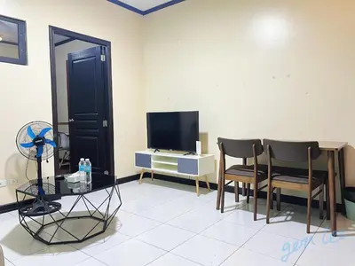 a living room with two chairs and a television at HOYA Aparthotel In Malate in Manila