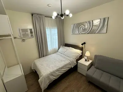 a small bedroom with a bed and a couch at Affordable Condo Near Nuvali in Silang