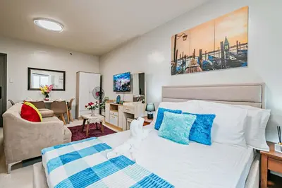 a bedroom with a bed and a living room at Coho The Hermosa - Staycation Studio Unit and Balcony View with Swimming Pool and Open Court access in Manila