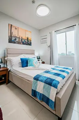 a bedroom with a large bed with blue pillows at Coho The Hermosa - Staycation Studio Unit and Balcony View with Swimming Pool and Open Court access in Manila