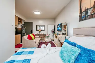 a bedroom with a bed and a living room at Coho The Hermosa - Staycation Studio Unit and Balcony View with Swimming Pool and Open Court access in Manila