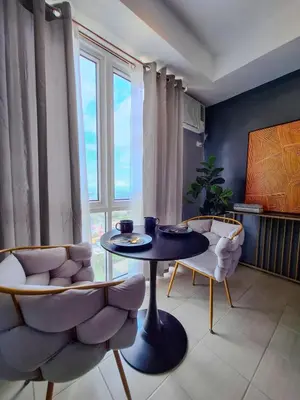 a living room with a table and chairs and a window at The French Apartment Pasig - Fast Wi-Fi and pool in Manila