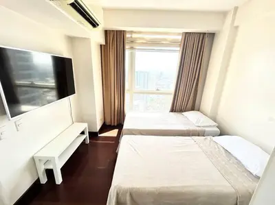 a hotel room with two beds and a window at 2 Bedroom Loft at Twin Oaks Place in Manila