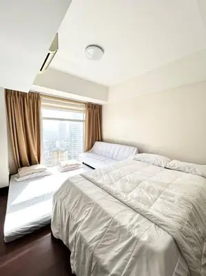 a bedroom with two beds and a window at 2 Bedroom Loft at Twin Oaks Place in Manila