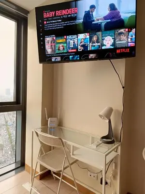 a television hanging on a wall above a glass desk at Eastwood Staycation Home with Stunning City View minimum 2nights stay in Manila