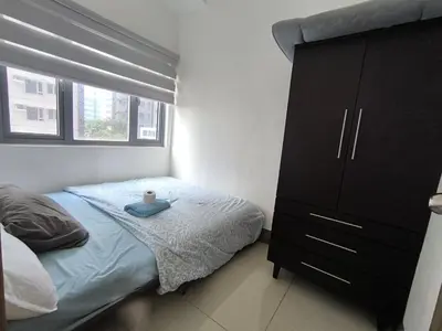 a bedroom with a bed and a dresser with a candle on it at Fame Residence 701 Tower 2 in Manila