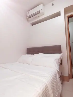 a bedroom with a white bed with a air conditioner at Condo near Mall of Asia in Manila