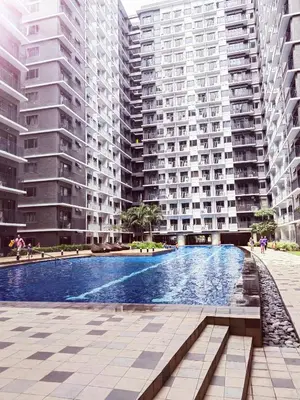 a swimming pool in the middle of two tall buildings at Condo near Mall of Asia in Manila
