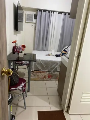 a small bedroom with a bed and a table with a desk at Pierrecondotel in Manila