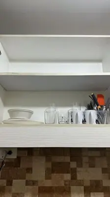 a white shelf with cups and utensils on it at Meowcation Condo in Makati in Manila