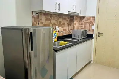 a kitchen with a stainless steel refrigerator and a microwave at Meowcation Condo in Makati in Manila