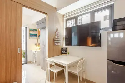 a small dining room with a table and a flat screen tv at ClaySky Staycation S2T1-Cozy & Homey 1BR Apartment near MOA facing Pool with Own Parking with Netflix, HBO Max YouTube Premium & up to 200mbps Wifi in Manila