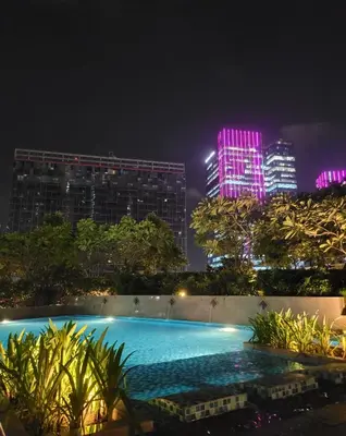 a swimming pool at night with buildings in the background at Staycations Up Above 14 @ BGC 1BR in Manila