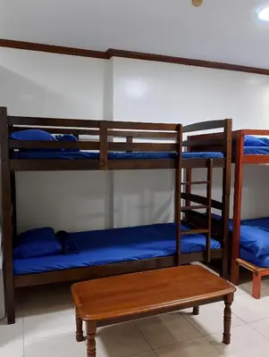 a room with three bunk beds and a wooden table at Makati Transient Condo 3BR with Balcony, Wifi in Manila