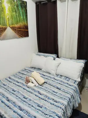 a bed with a blue and white blanket and pillows at Nicecondotel in Manila