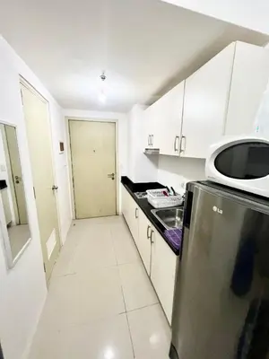 a white kitchen with a refrigerator and a microwave at Cozy Studio with SM Jazz Mall 