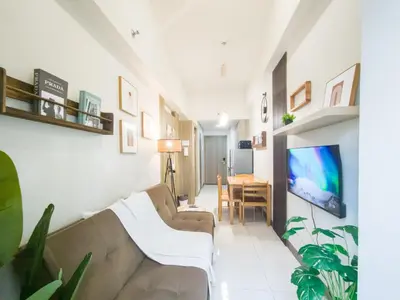 a living room with a couch and a tv on a wall at GemstoneBR in SMDC Coast Residences in Manila