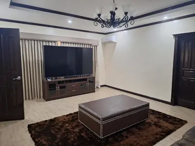 a living room with a large television and a brown ottoman at La Dolce Vita Villa in Santa Rosa