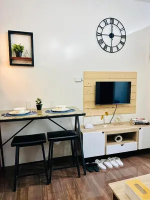 a living room with a table and a clock on the wall at Mon ciel suite Spacious 1BR Air Residence SMDC in Manila