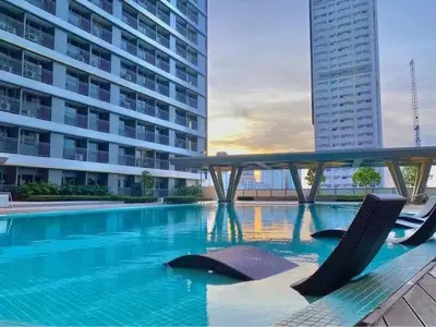 a swimming pool with two chairs and a building at 1BR w/ Balcony near Megamall: The Admiral‘s Lounge in Manila
