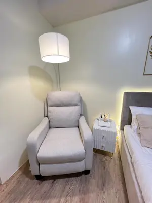 a bedroom with a chair and a bed and a lamp at Condo near Nuvali Laguna Technopark St Benedict Church in Bayabasan
