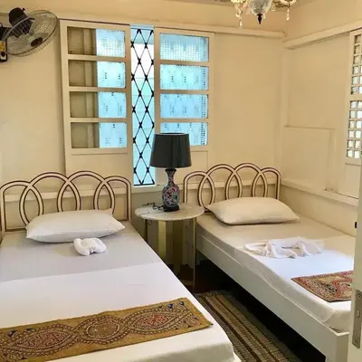 two beds in a room with two windows at Courtyard Hotel in Manila