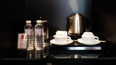 a counter with a coffee maker and bottles of water at Amelie Hotel Manila in Manila
