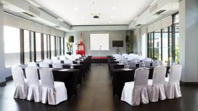 a room with rows of tables and white chairs at Amelie Hotel Manila in Manila