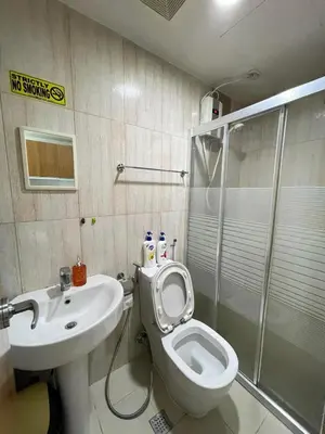 a bathroom with a toilet and a sink and a shower at Staycation near SLMEC, US Embassy and Supreme Court in Manila