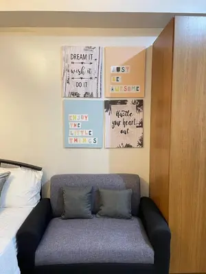 a couch in a room with posters on the wall at Staycation near SLMEC, US Embassy and Supreme Court in Manila