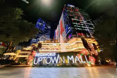 a building with a sign that reads metropolitan uptown mall at night at Cozy Stay In Bgc Near Uptown Mall #oursw11d1 in Manila